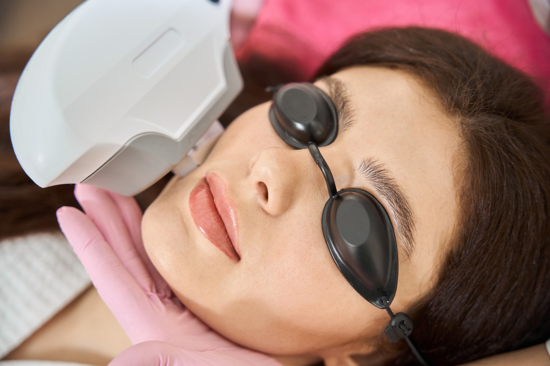 Image of an IPL device being used on a patient's face. A skincare professional performing IPL therapy on a patient's face, targeting pigmentation and skin imperfections with an Intense Pulsed Light device.